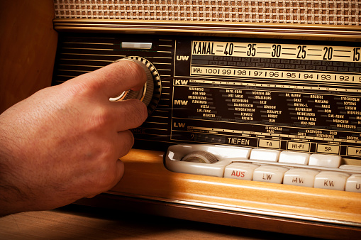 man turning volume control button of a old fashioned radio